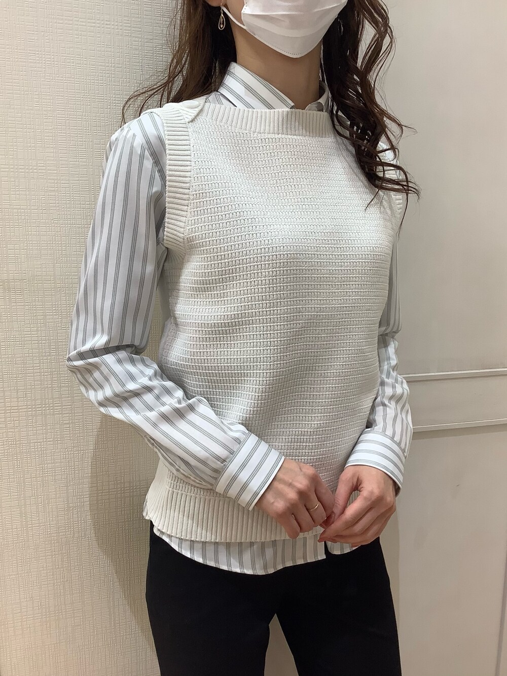 ホワイト系のベスト、グリーン系のビジネスシャツを着用したレディースの春コーディネートの2枚目の写真