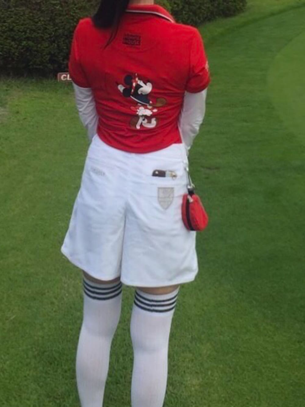 レッド系のポロシャツ、ホワイト系のスカート、ホワイト系のレッグウェアを着用したレディースの秋コーディネートの3枚目の写真