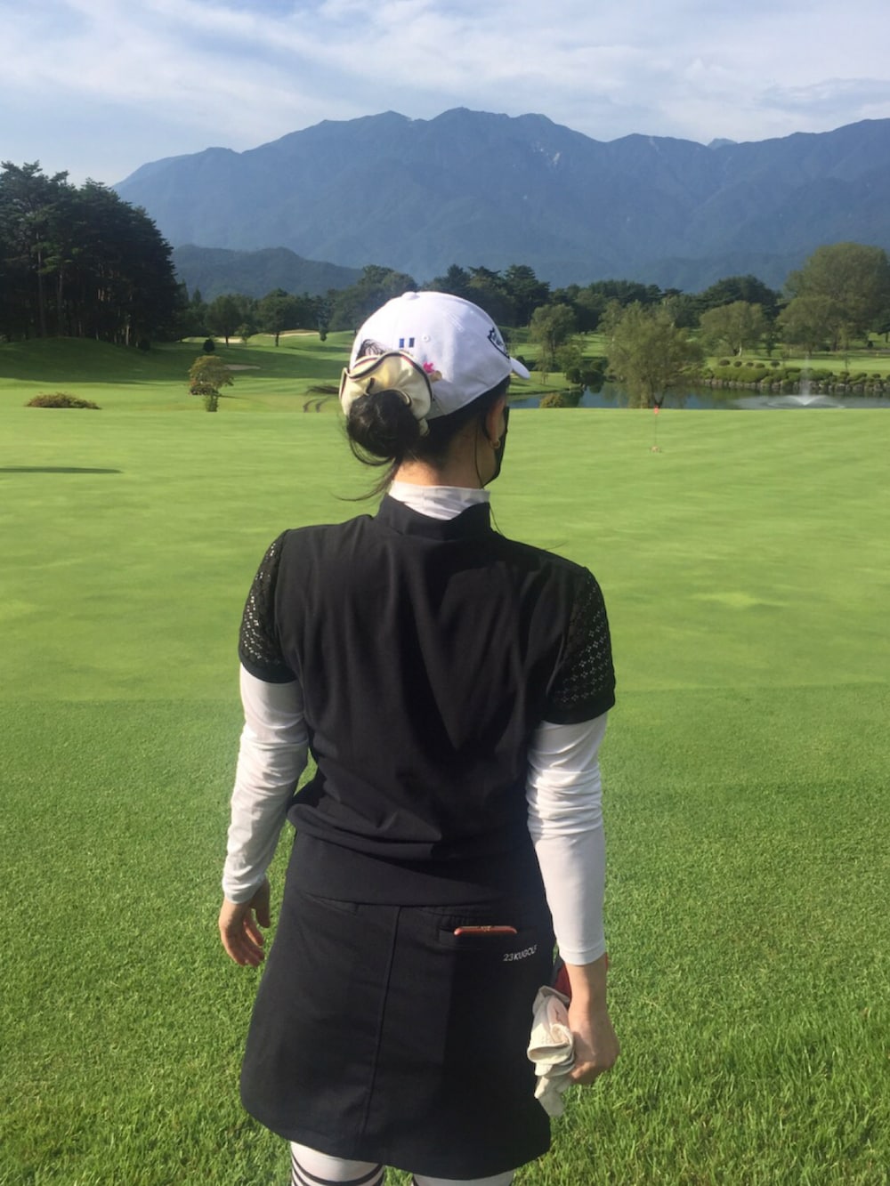 ブラック系のトップス、ブラック系のスカート、ホワイト系のレッグウェアを着用したレディースの夏コーディネートの2枚目の写真