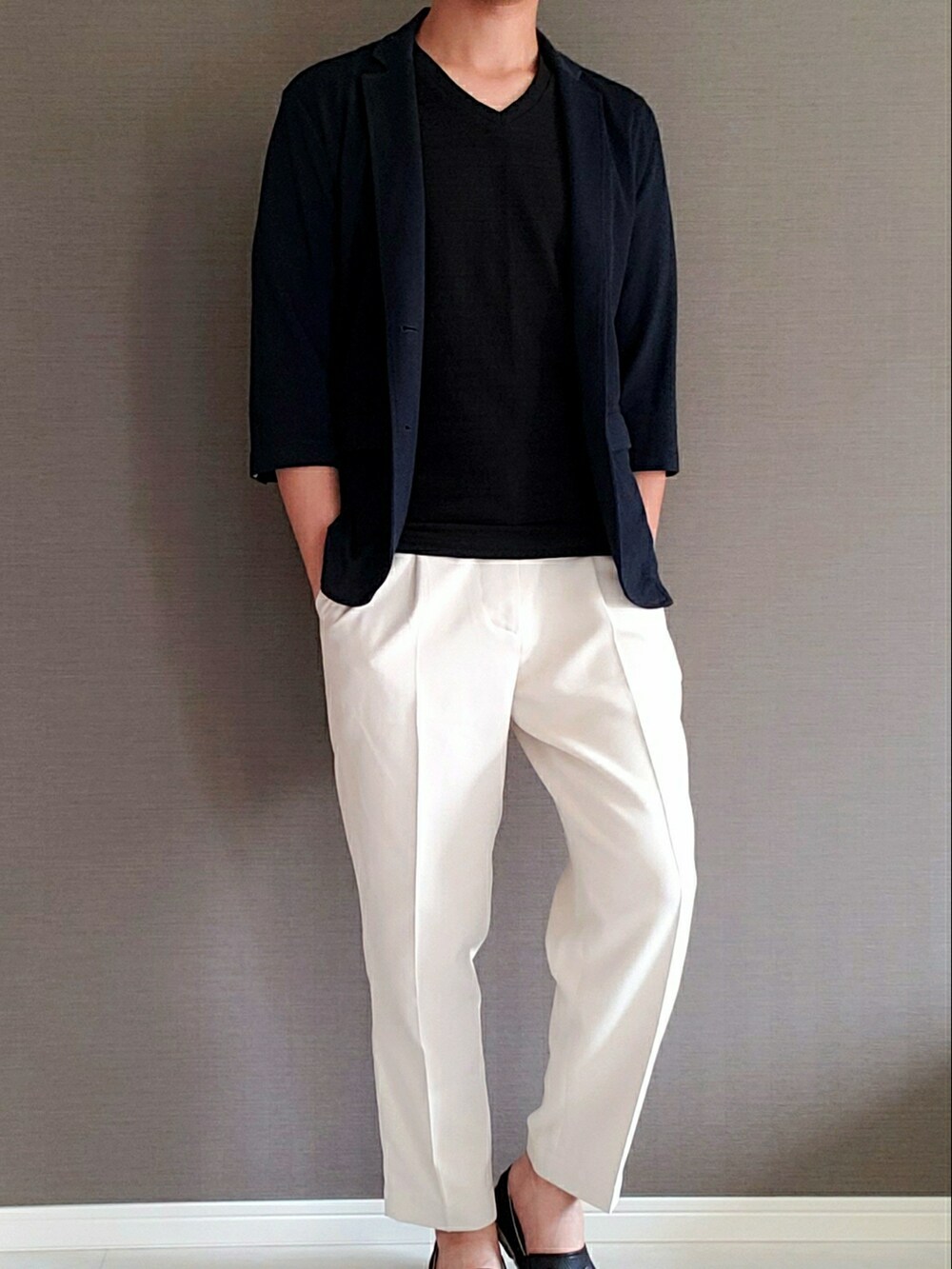 ホワイト系のスラックス、ブラック系のスリッポン、ブラック系のTシャツ/カットソーを着用したメンズの夏コーディネートの2枚目の写真