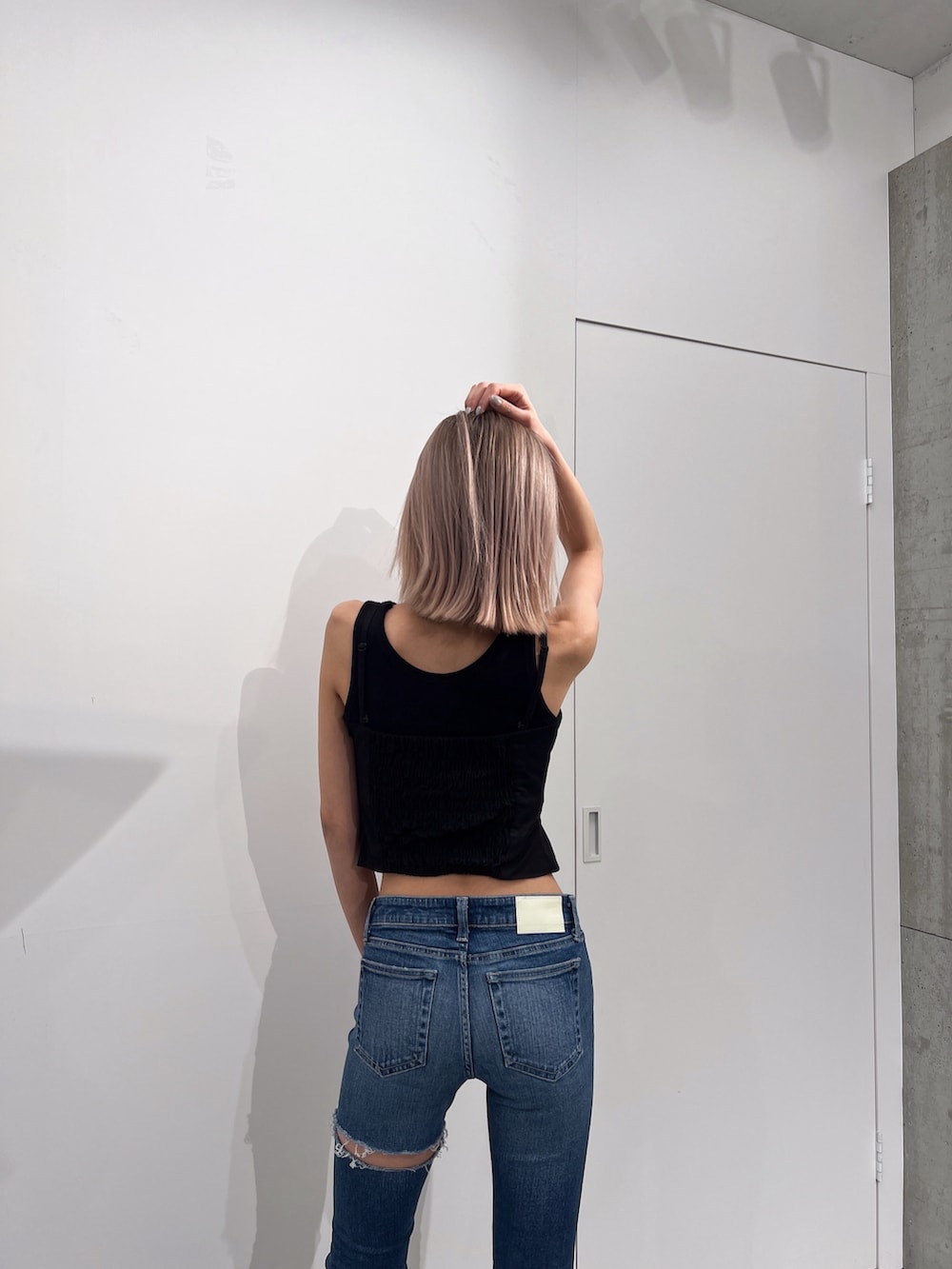 ブラック系のタンクトップ、ブルー系のデニムパンツ、ブラック系のパンプスを着用したレディースの夏コーディネートの3枚目の写真