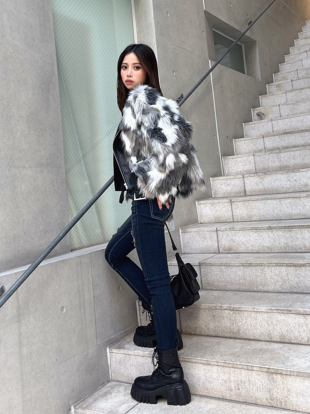 ブルー系のデニムパンツ、ブラック系のブーツ、ブラウン系のハンドバッグを着用したレディースの秋コーディネートの2枚目の写真