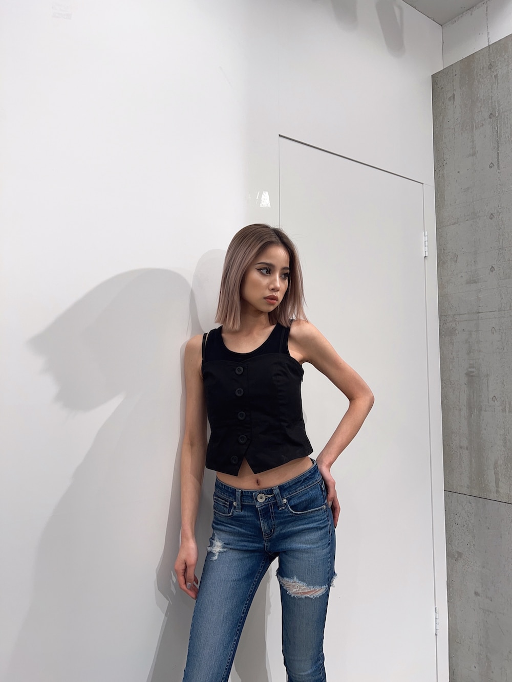 ブラック系のタンクトップ、ブルー系のデニムパンツ、ブラック系のパンプスを着用したレディースの夏コーディネートの4枚目の写真