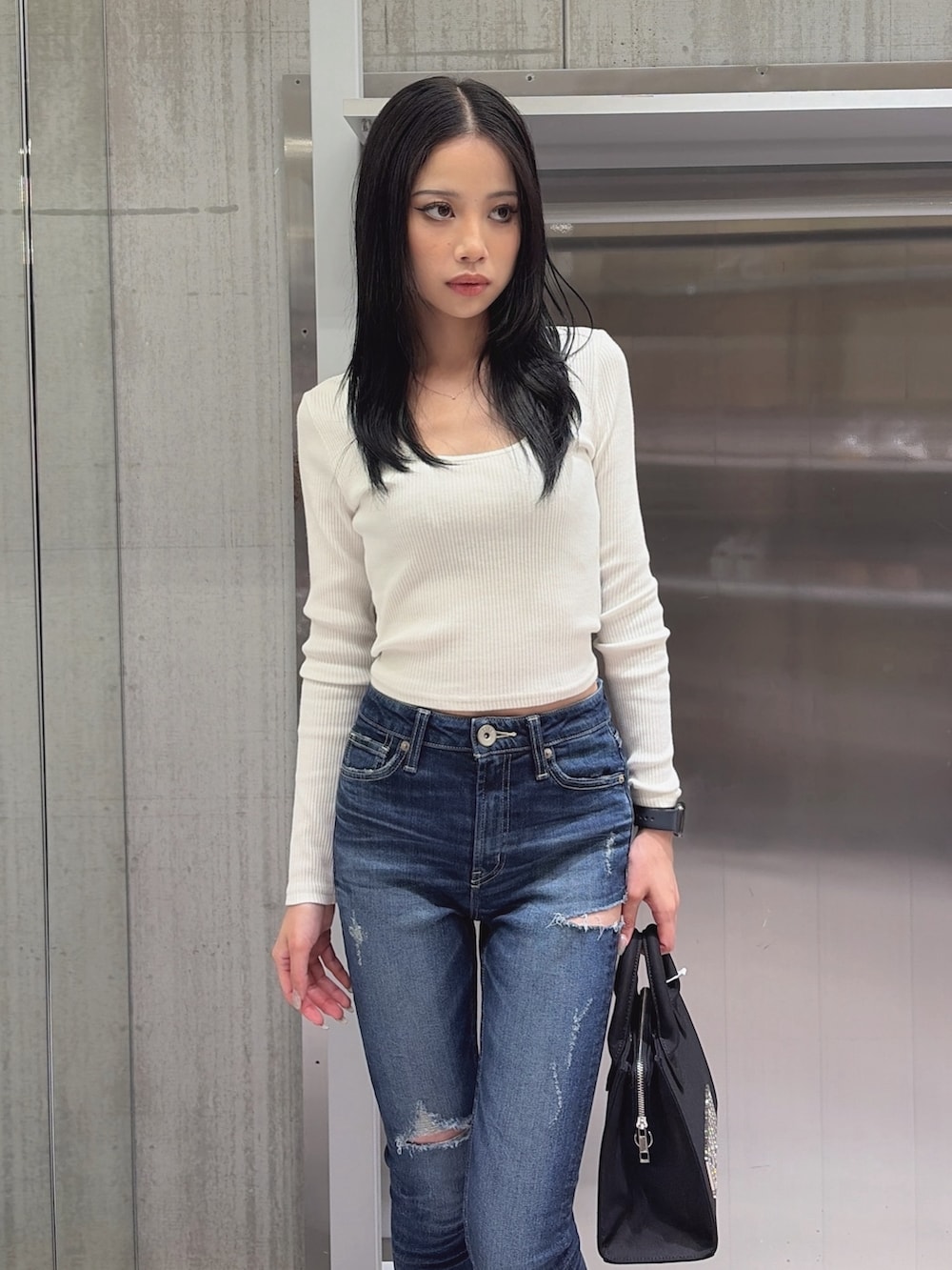 ブルー系のデニムパンツ、ブラック系のハンドバッグ、ブラック系のブーツを着用したレディースの秋コーディネートの4枚目の写真