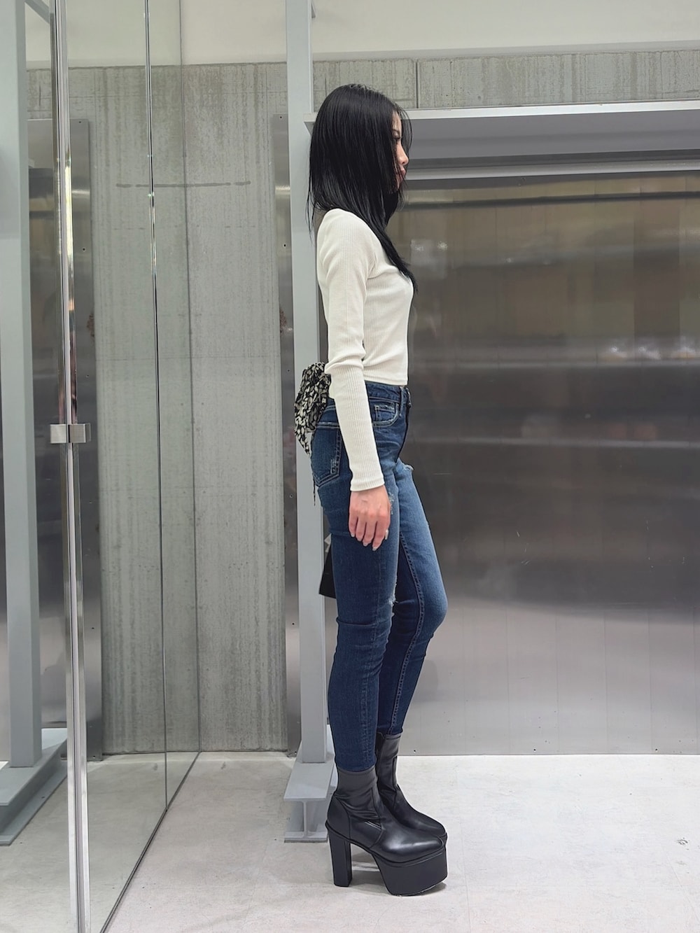 ブルー系のデニムパンツ、ブラック系のハンドバッグ、ブラック系のブーツを着用したレディースの秋コーディネートの2枚目の写真