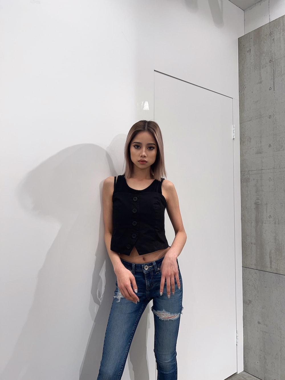 ブラック系のタンクトップ、ブルー系のデニムパンツ、ブラック系のパンプスを着用したレディースの夏コーディネートの5枚目の写真