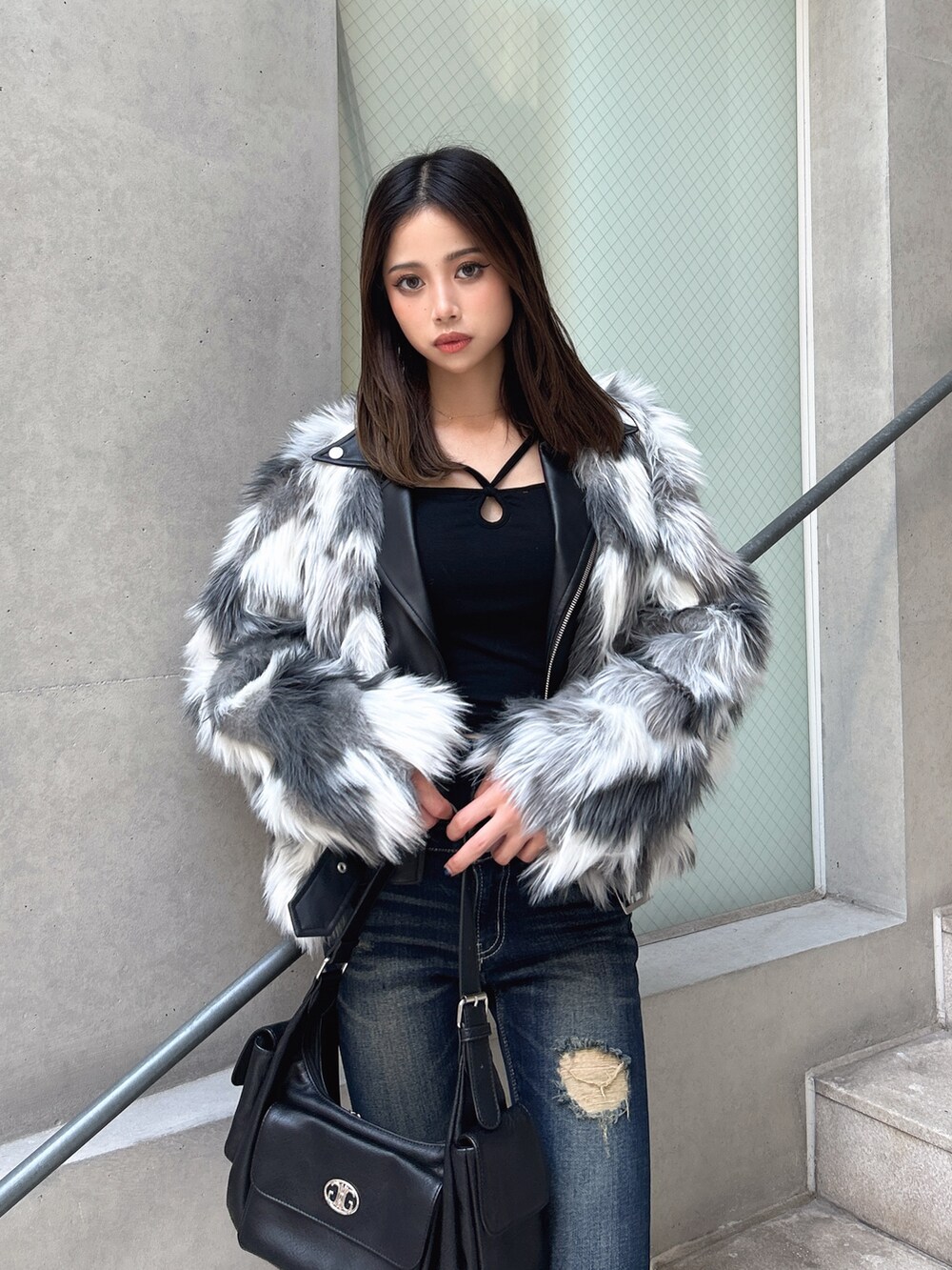 ブルー系のデニムパンツ、ブラック系のブーツ、ブラウン系のハンドバッグを着用したレディースの秋コーディネートの3枚目の写真