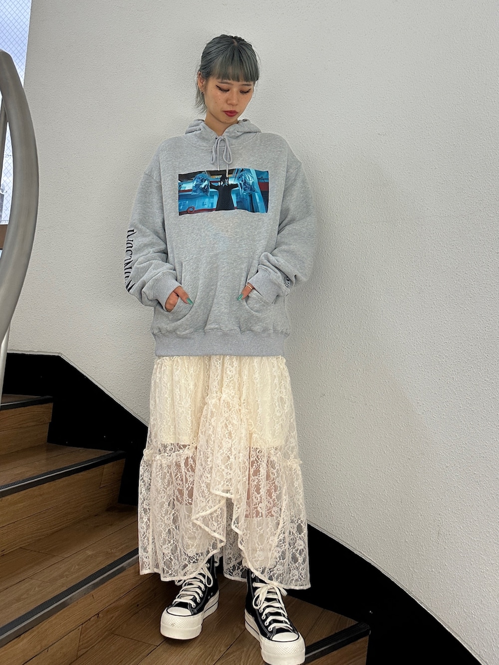 グレー系のパーカー、ホワイト系のスカート、ブラック系のスニーカーを着用したレディースの秋コーディネートの2枚目の写真