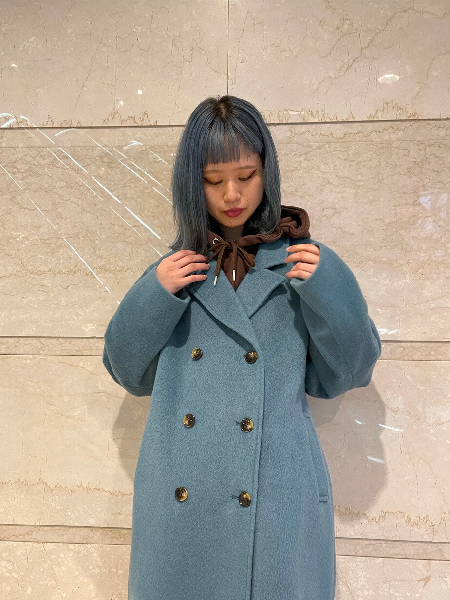 ブルー系のチェスターコート、ブラウン系のパーカー、ブラウン系のブーツを着用したレディースの冬コーディネートの3枚目の写真