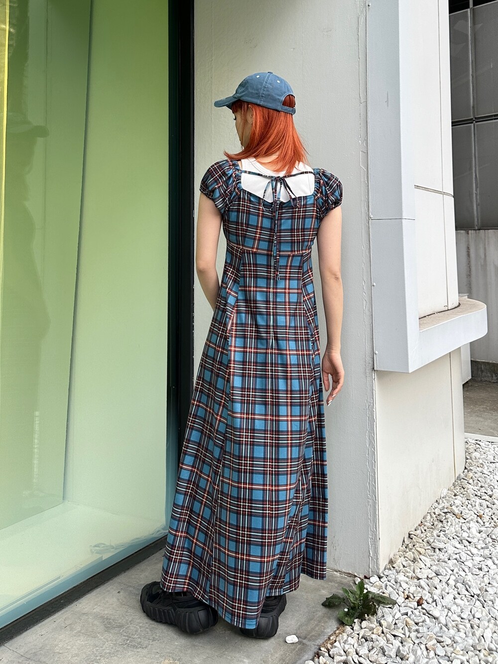 ブルー系のワンピース、ブラック系のスニーカー、ブルー系のキャップを着用したレディースの春コーディネートの3枚目の写真