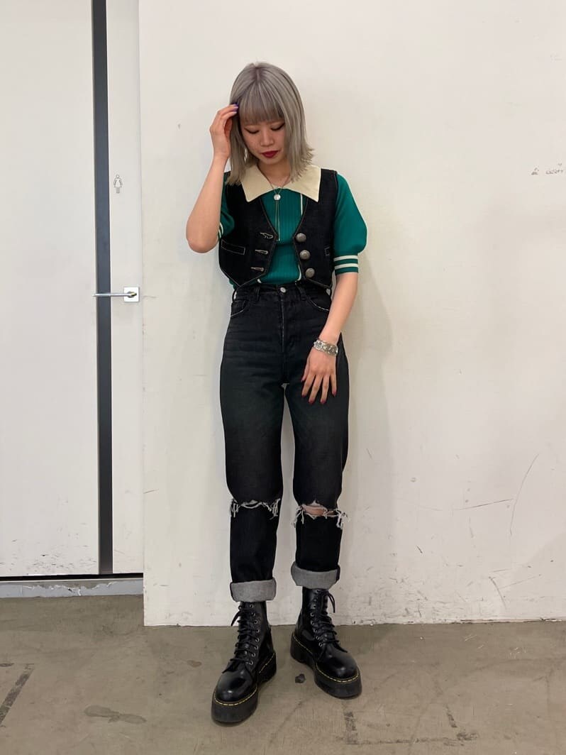 ブラック系のデニムパンツ、ブラック系のブーツ、ブラック系のベストを着用したレディースの春コーディネートの2枚目の写真