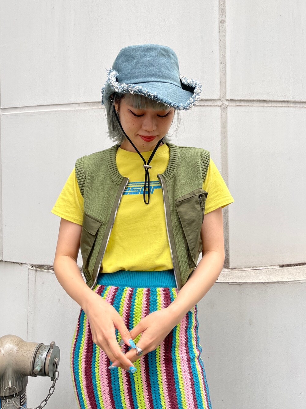 イエロー系のTシャツ/カットソー、グリーン系のベスト、ブルー系のスカートを着用したレディースの春コーディネートの7枚目の写真