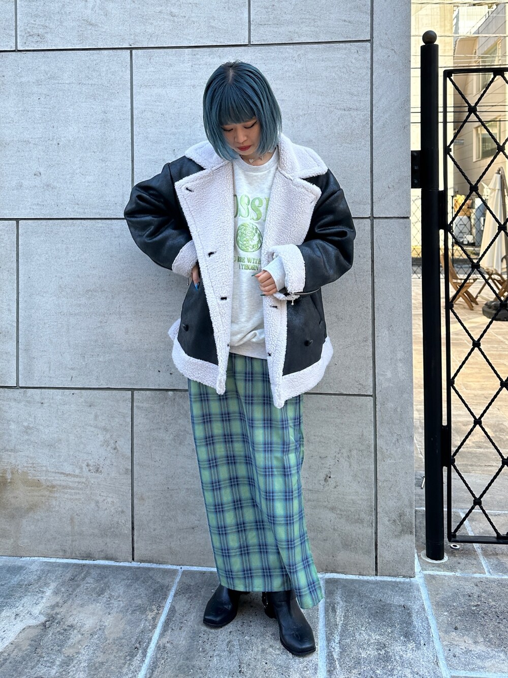 ブラック系のムートンコート、グレー系のスウェット、グリーン系のワンピースを着用したレディースの冬コーディネートの2枚目の写真