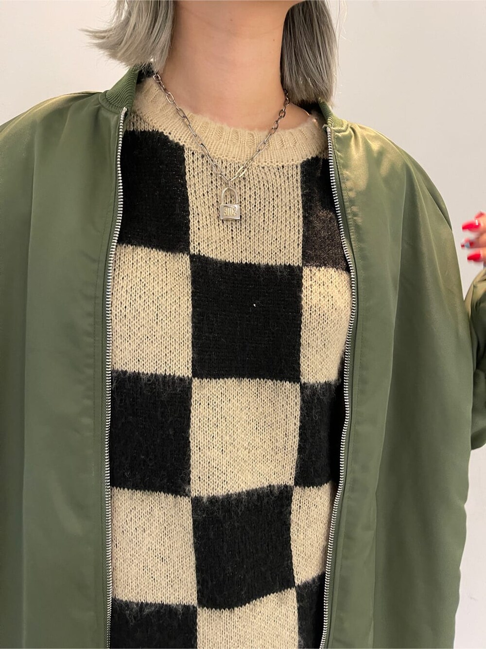 ブラック系のニット/セーター、グリーン系のMA-1、グリーン系のスカートを着用したレディースの秋コーディネートの7枚目の写真