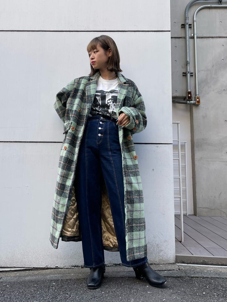 グリーン系のチェスターコート、ブラック系のブーツ、ブルー系のデニムパンツを着用したレディースの秋コーディネートの2枚目の写真