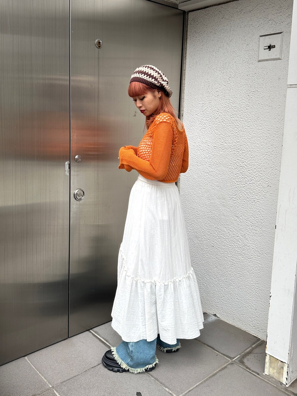 オレンジ系のカーディガン/ボレロ、ホワイト系のスカート、ブルー系のデニムパンツを着用したレディースの冬コーディネートの5枚目の写真