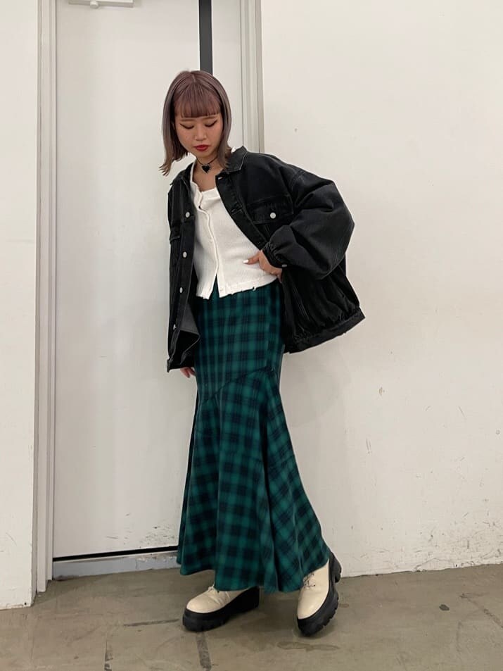 グリーン系のスカート、ブラック系のデニムジャケット、ホワイト系のブーツを着用したレディースの冬コーディネートの2枚目の写真