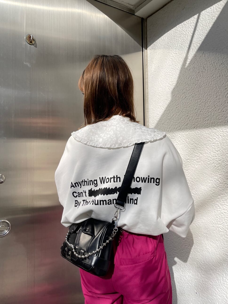 ピンク系のスラックス、ブラック系のショルダーバッグ、ホワイト系のスウェットを着用したレディースの冬コーディネートの5枚目の写真