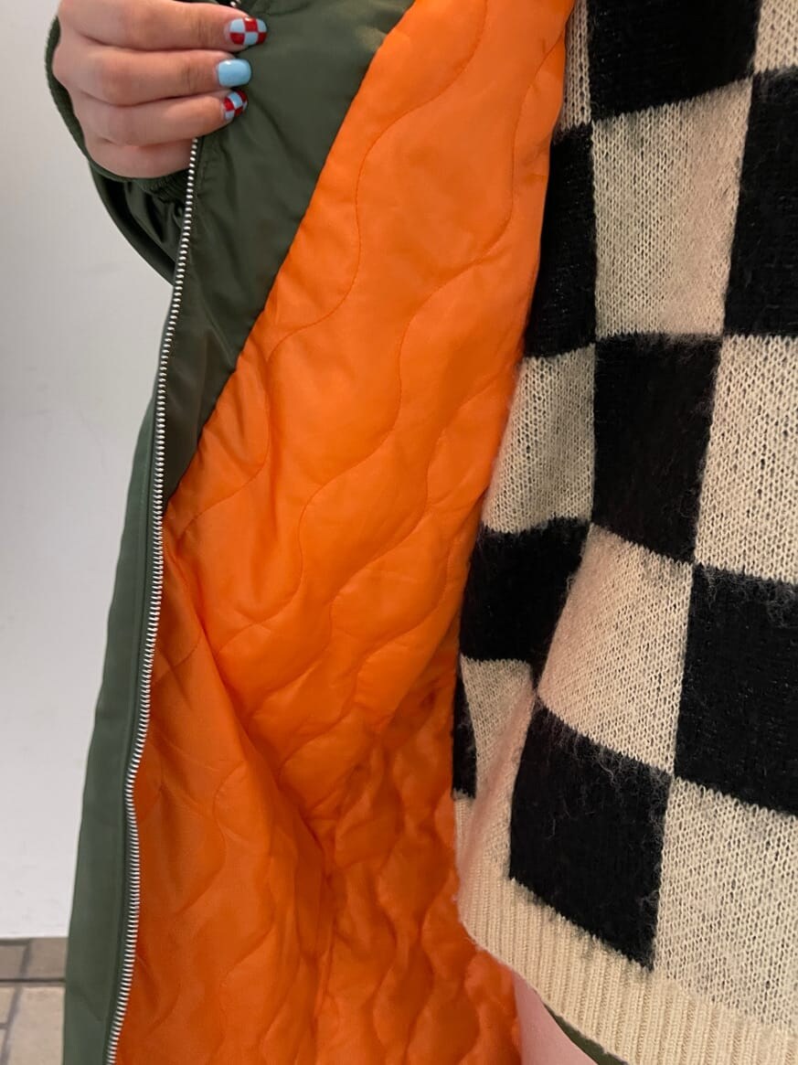 ブラック系のニット/セーター、グリーン系のMA-1、グリーン系のスカートを着用したレディースの秋コーディネートの9枚目の写真