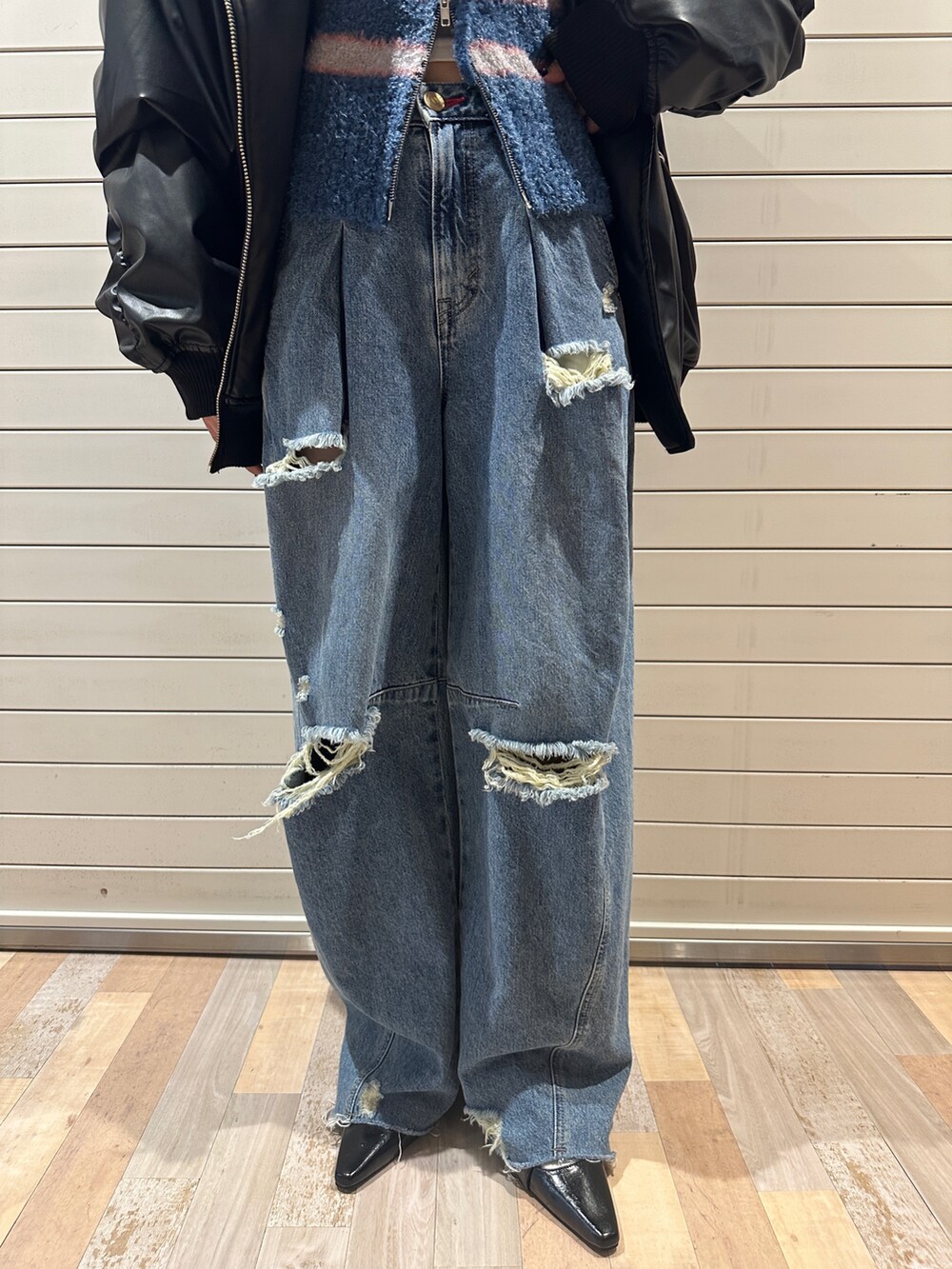 ブラック系のブルゾン、ブルー系のパーカー、ブルー系のデニムパンツを着用したレディースの秋コーディネートの10枚目の写真