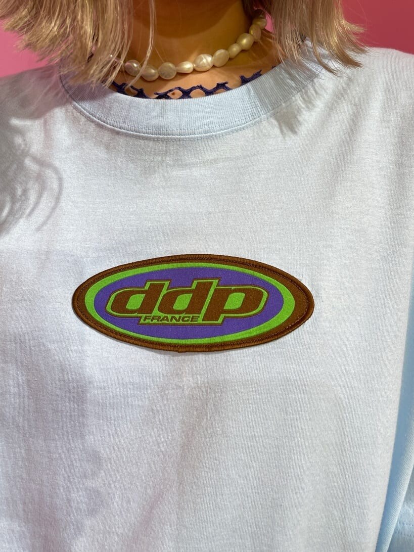 ブラック系のデニムパンツ、ブラック系のその他シューズ、パープル系のTシャツ/カットソーを着用したレディースの春コーディネートの6枚目の写真