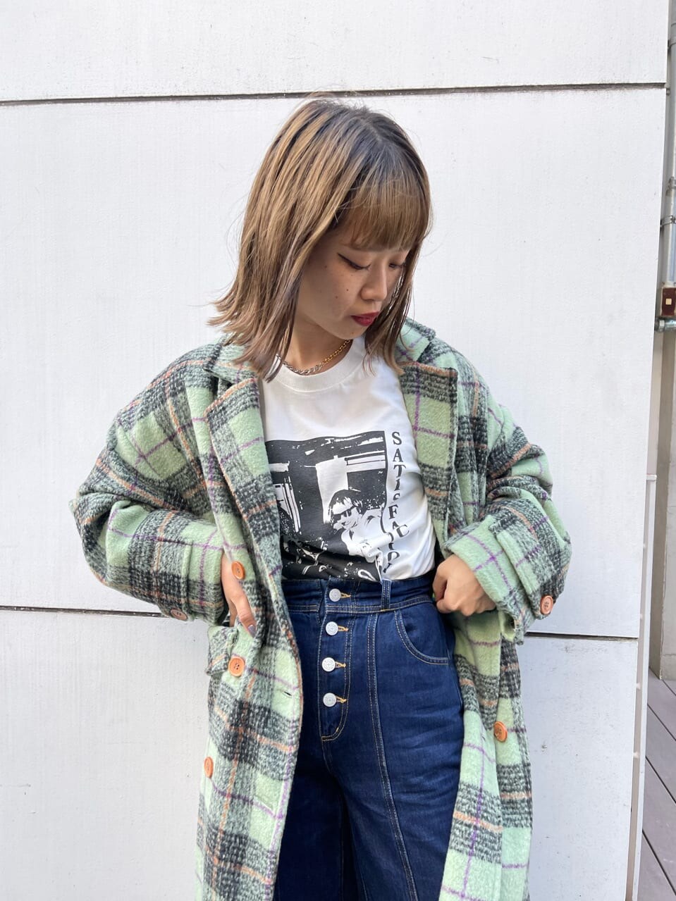 グリーン系のチェスターコート、ブラック系のブーツ、ブルー系のデニムパンツを着用したレディースの秋コーディネートの5枚目の写真