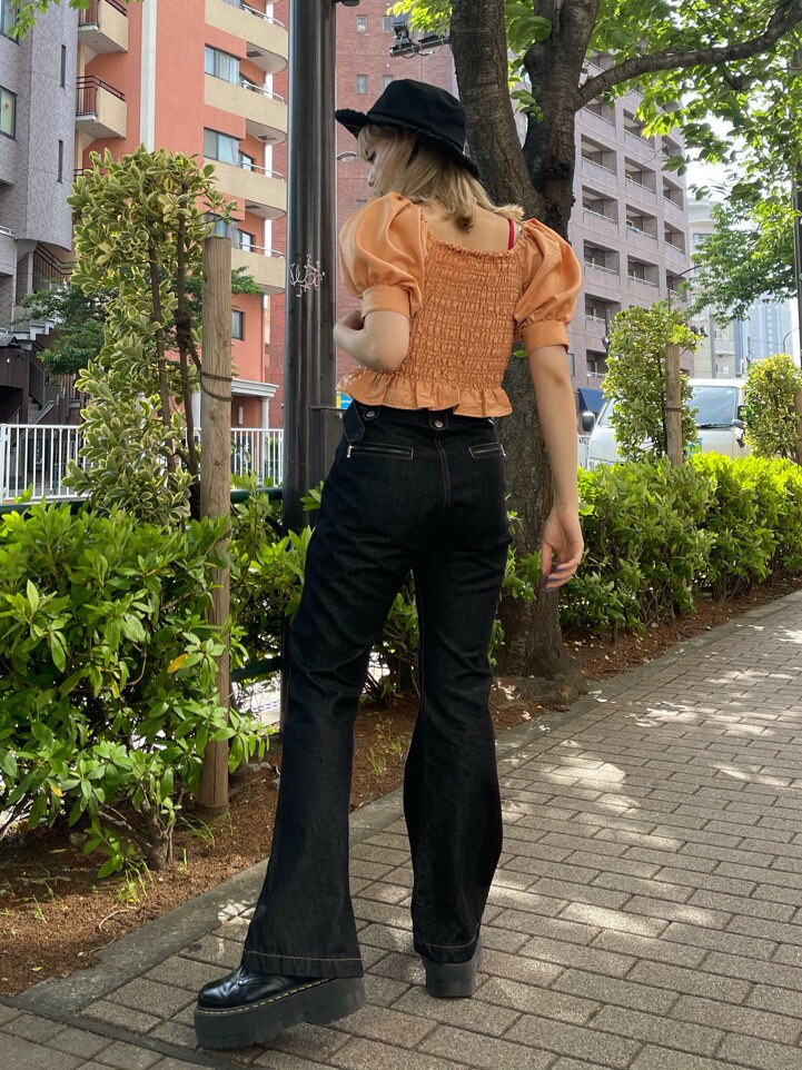 オレンジ系のシャツ/ブラウス、ブラック系のデニムパンツ、ブラック系のハットを着用したレディースの春コーディネートの4枚目の写真