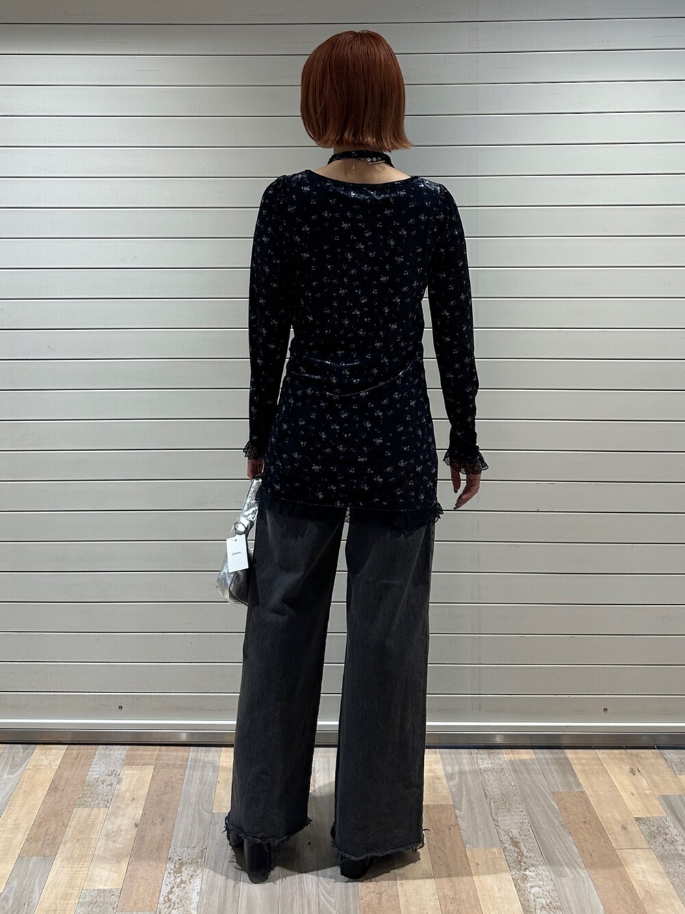 ブルー系のワンピース、シルバー系のハンドバッグ、ブラック系のデニムパンツを着用したレディースの冬コーディネートの4枚目の写真