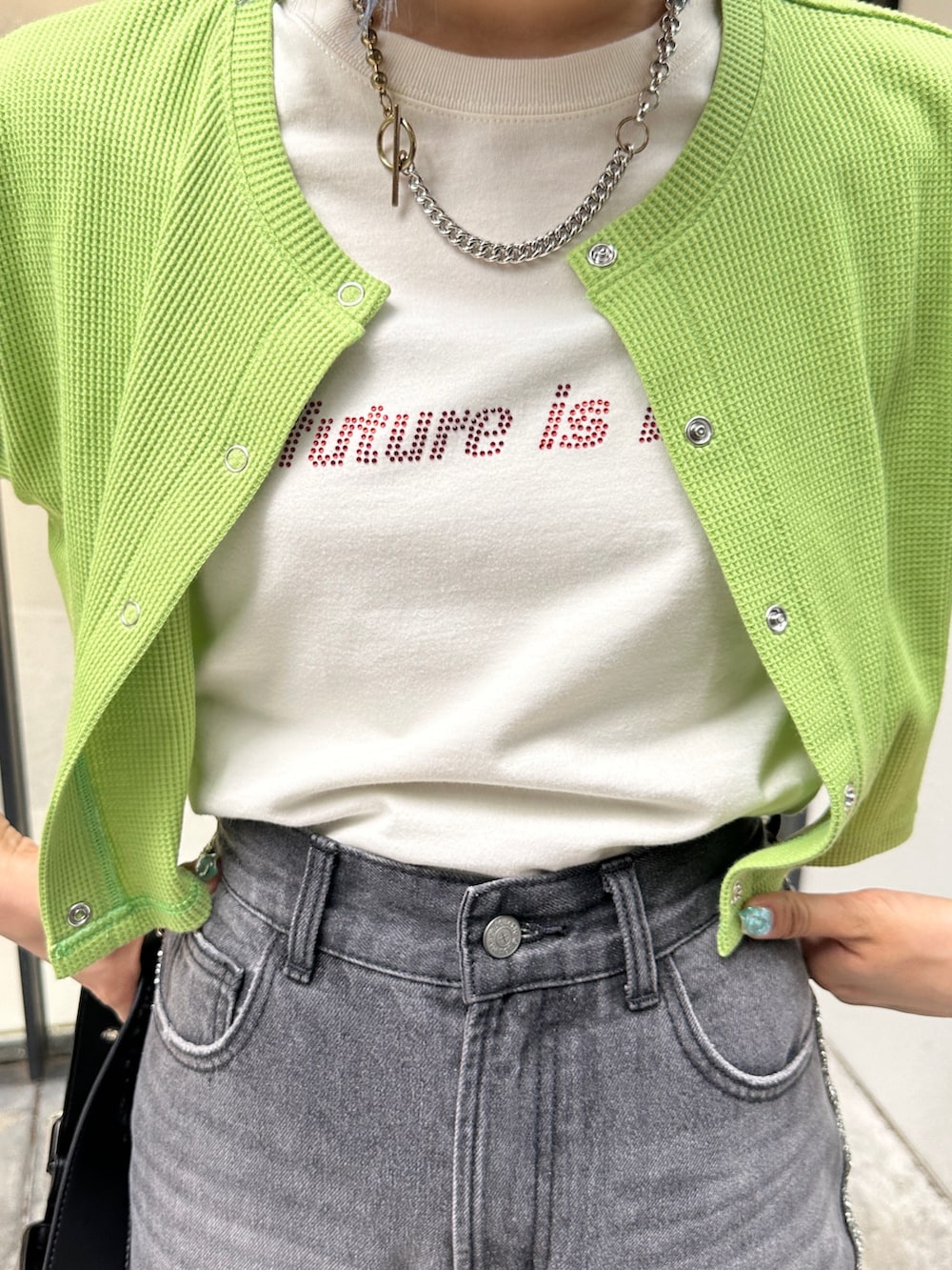 グリーン系のTシャツ/カットソー、ブラック系のデニムパンツ、ブラック系のハンドバッグを着用したレディースの夏コーディネートの7枚目の写真