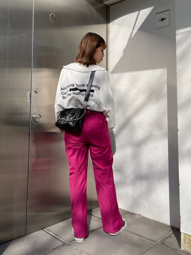 ピンク系のスラックス、ブラック系のショルダーバッグ、ホワイト系のスウェットを着用したレディースの冬コーディネートの3枚目の写真