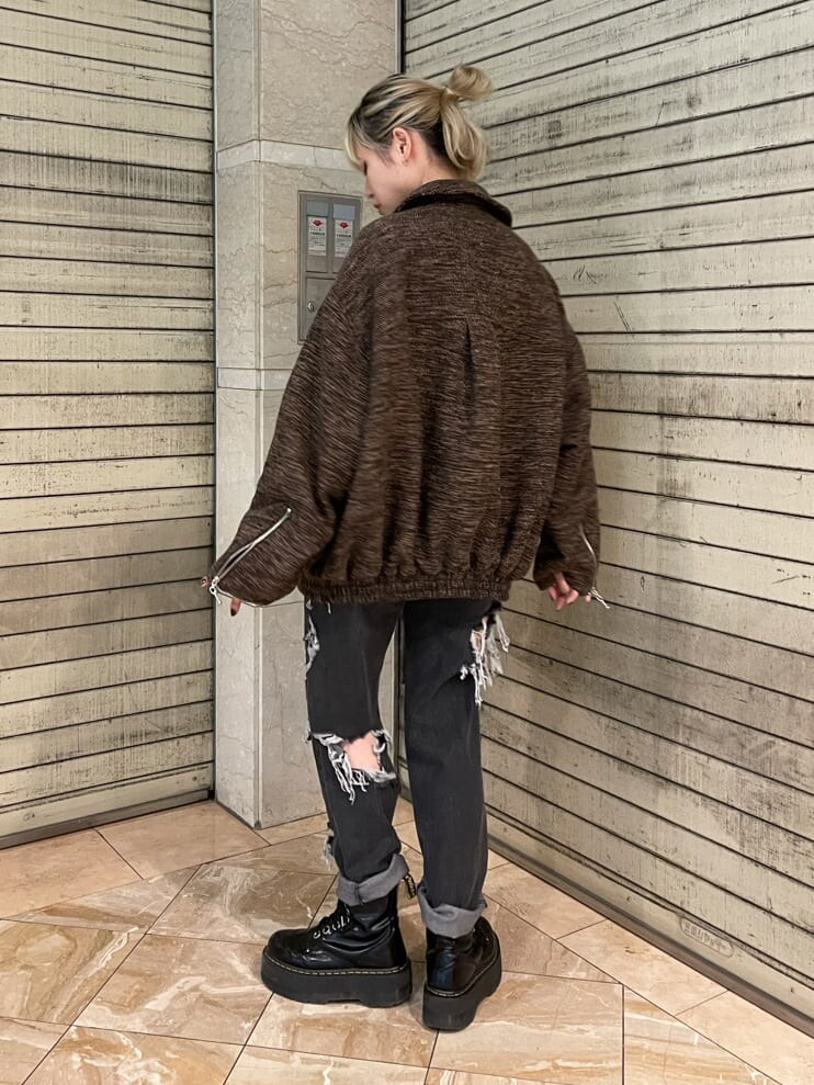 ブラック系のブーツ、ブラック系のデニムパンツ、ブラウン系のブルゾンを着用したレディースの夏コーディネートの3枚目の写真