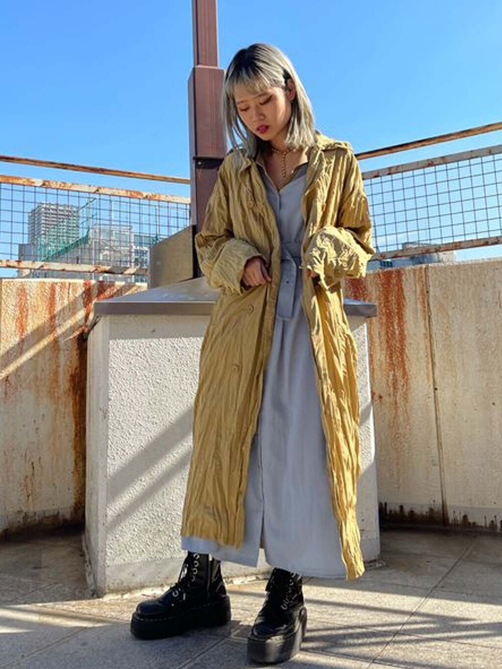 ベージュ系のトレンチコート、ブルー系のワンピースを着用したレディースの冬コーディネートの2枚目の写真