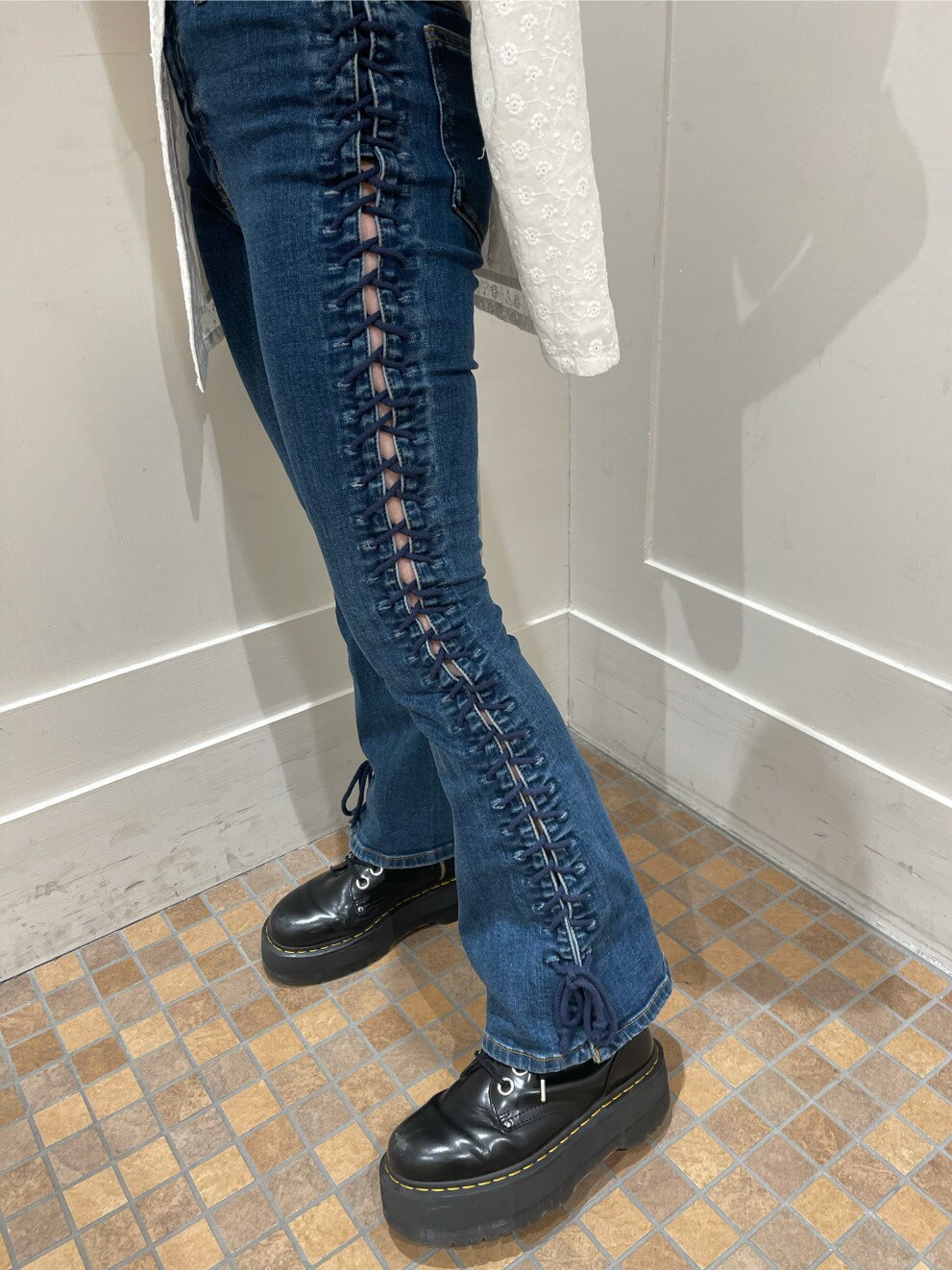 ブラック系のブーツ、ホワイト系のワンピース、ブルー系のデニムパンツを着用したレディースの春コーディネートの6枚目の写真