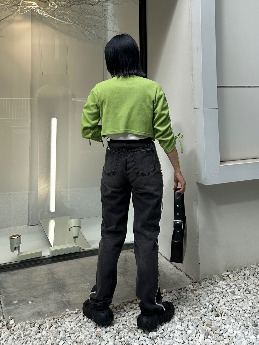 グリーン系のTシャツ/カットソー、ブラック系のデニムパンツ、ブラック系のハンドバッグを着用したレディースの夏コーディネートの4枚目の写真