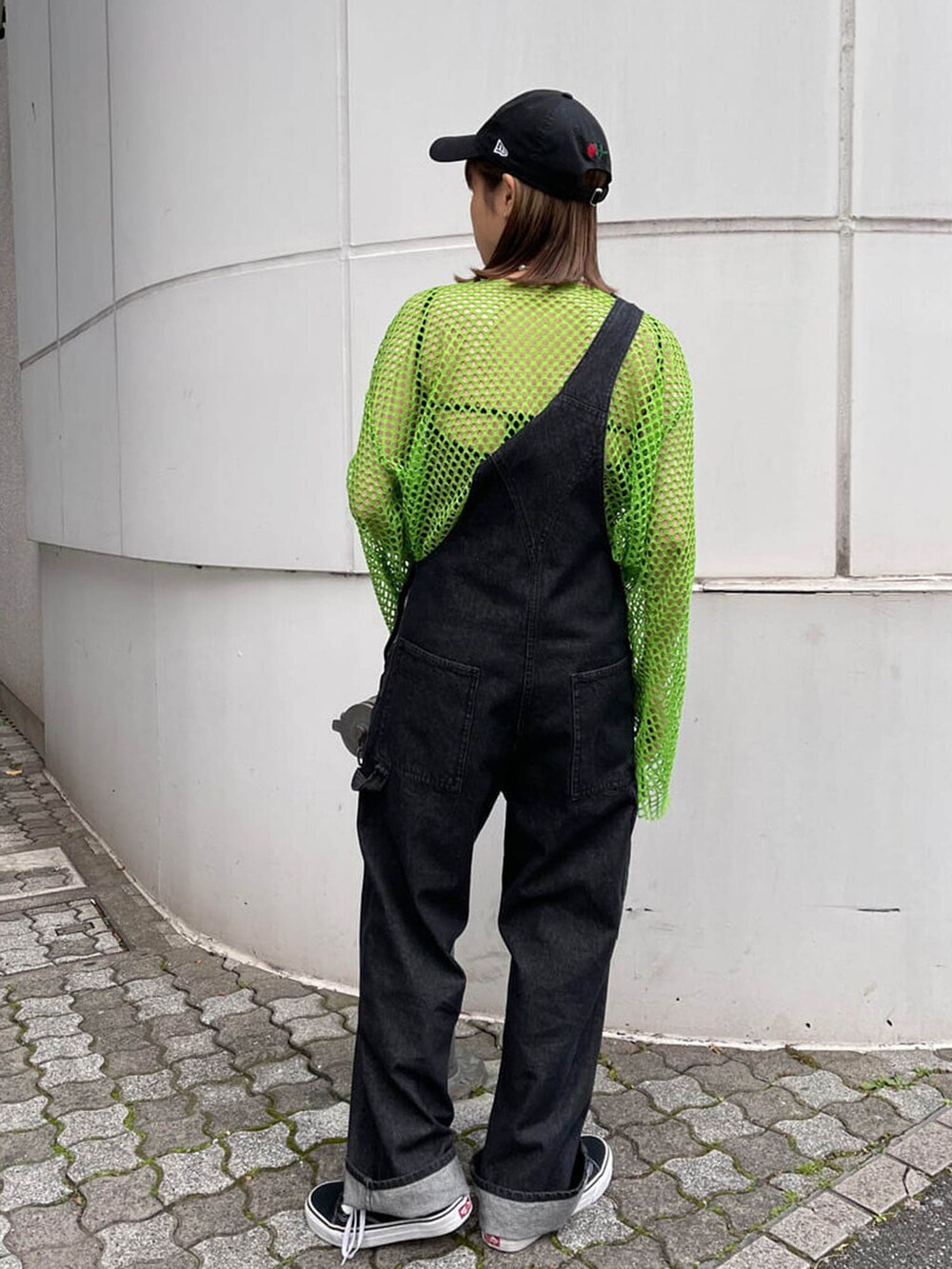 ブラック系のサロペット/オーバーオール、グリーン系のTシャツ/カットソー、ブラック系のキャップを着用したレディースの冬コーディネートの4枚目の写真