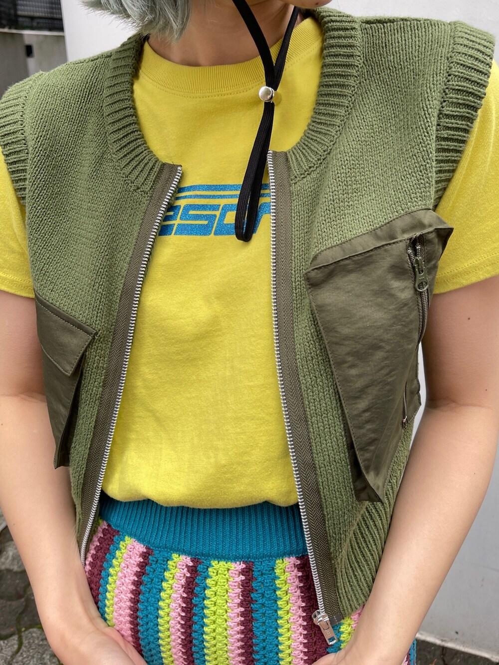 イエロー系のTシャツ/カットソー、グリーン系のベスト、ブルー系のスカートを着用したレディースの春コーディネートの9枚目の写真