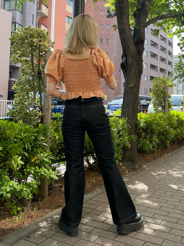 オレンジ系のシャツ/ブラウス、ブラック系のデニムパンツ、ブラック系のハットを着用したレディースの春コーディネートの2枚目の写真