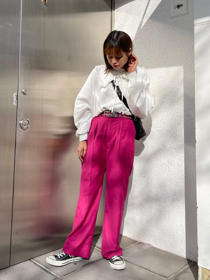 ピンク系のスラックス、ブラック系のショルダーバッグ、ホワイト系のスウェットを着用したレディースの冬コーディネートの2枚目の写真