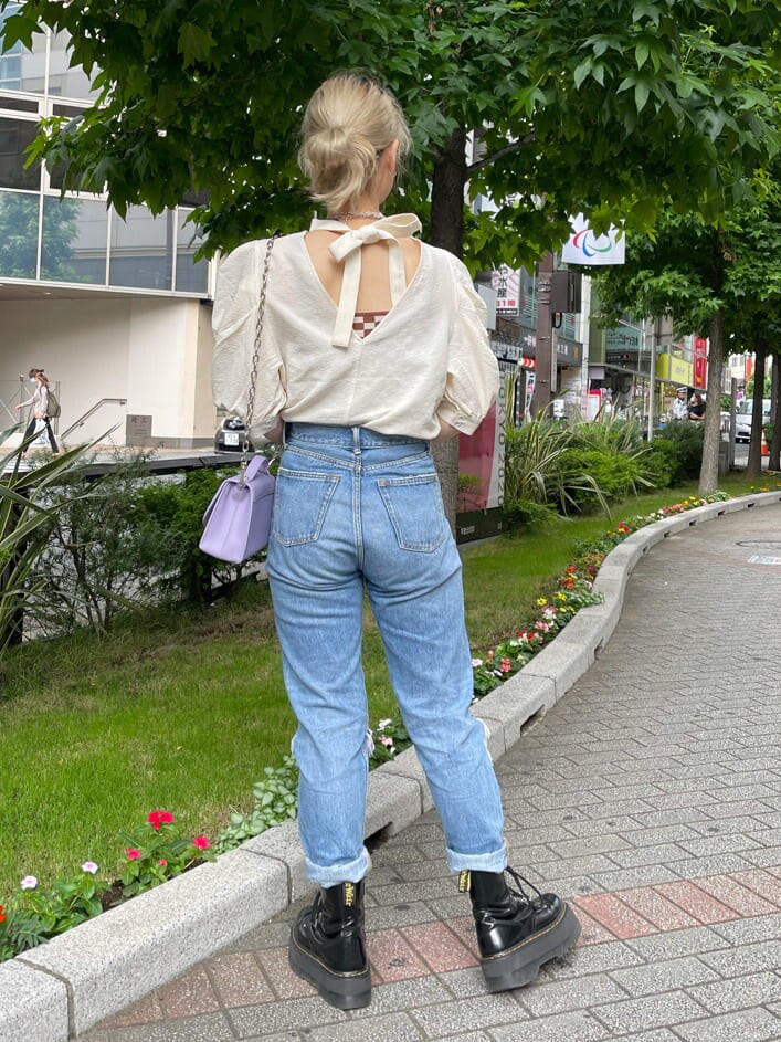 パープル系のショルダーバッグ、ホワイト系のシャツ/ブラウス、ブルー系のデニムパンツを着用したレディースの夏コーディネートの3枚目の写真