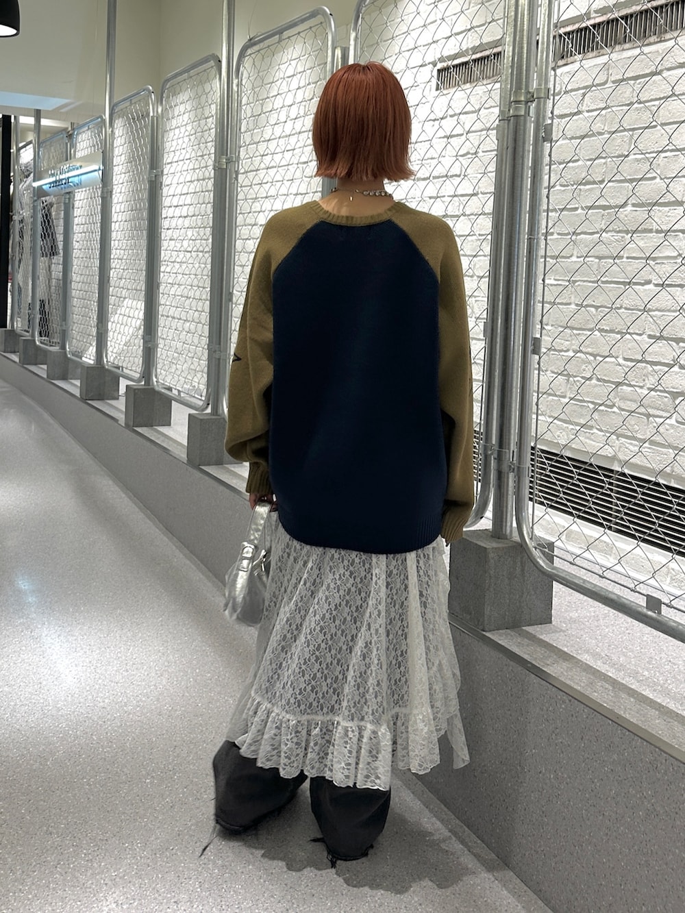 ブルー系のニット/セーター、ホワイト系のスカート、ブラック系のデニムパンツを着用したレディースの冬コーディネートの3枚目の写真