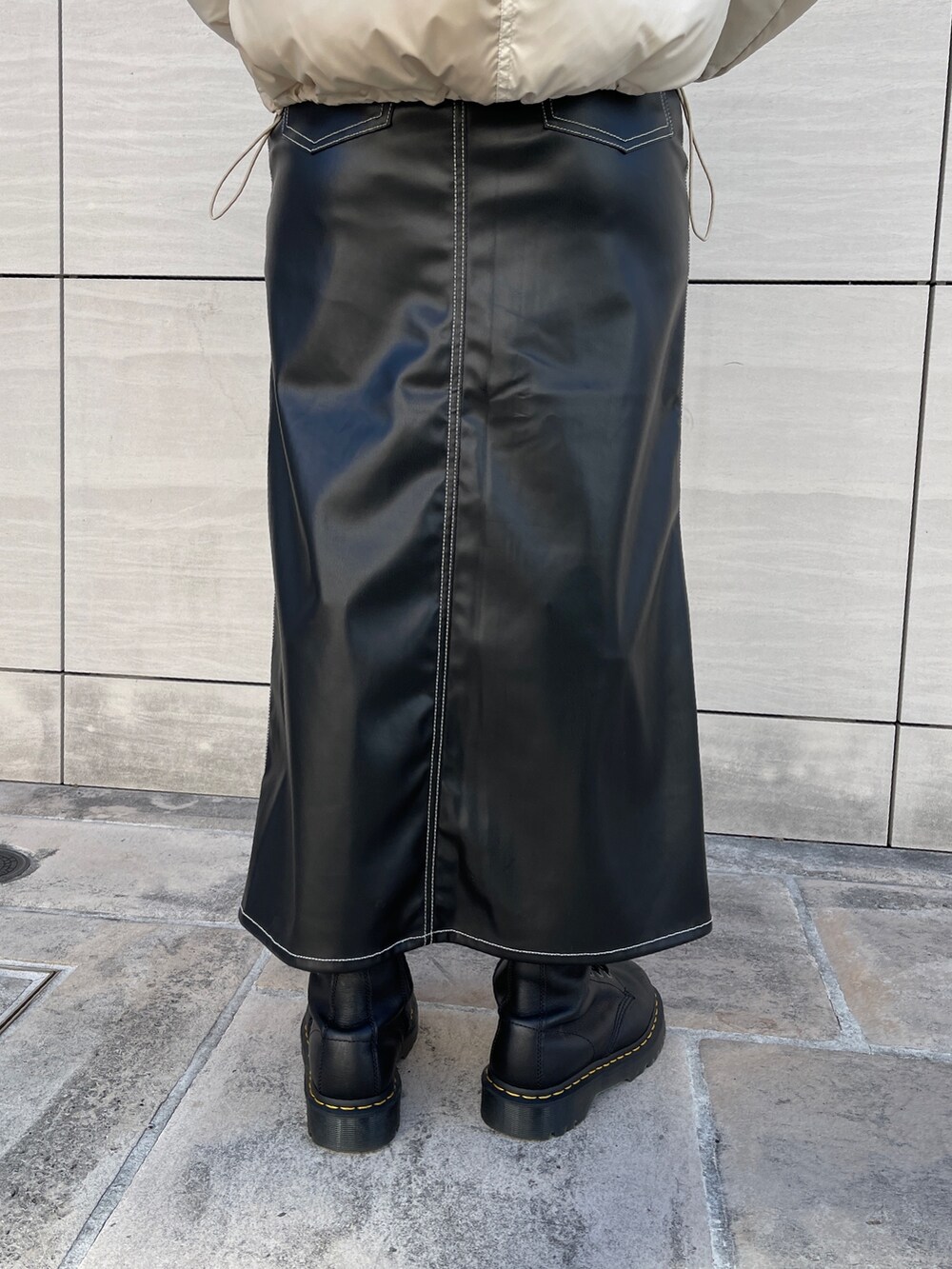 ホワイト系のTシャツ/カットソー、ブラック系のスカート、ブラック系のブーツを着用したレディースの秋コーディネートの9枚目の写真