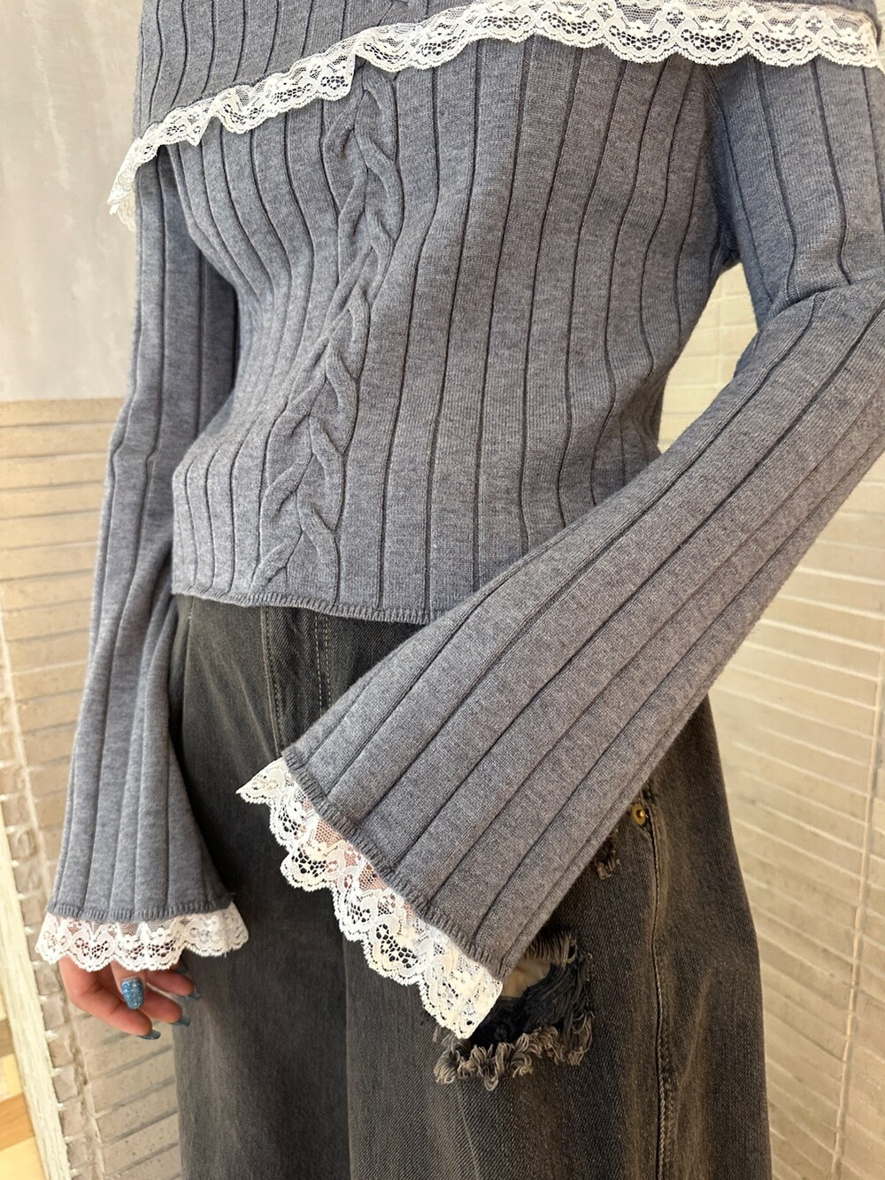 グレー系のニット/セーター、ブラック系のデニムパンツ、ブラック系のブーツを着用したレディースの冬コーディネートの9枚目の写真