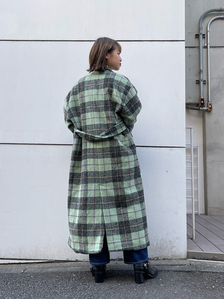 グリーン系のチェスターコート、ブラック系のブーツ、ブルー系のデニムパンツを着用したレディースの秋コーディネートの3枚目の写真