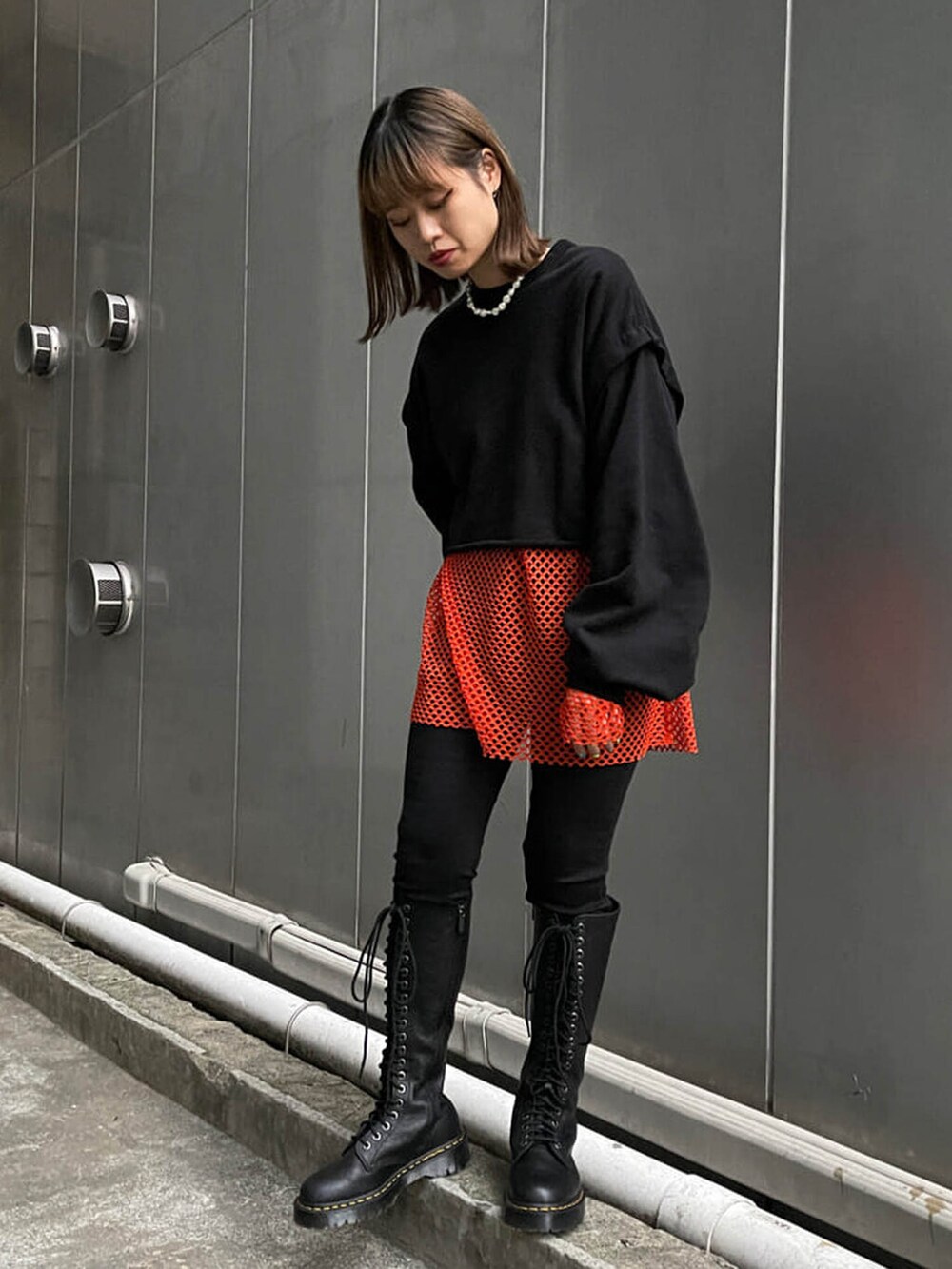 ブラック系のブーツ、ブラック系のTシャツ/カットソー、オレンジ系のTシャツ/カットソーを着用したレディースの冬コーディネートの4枚目の写真