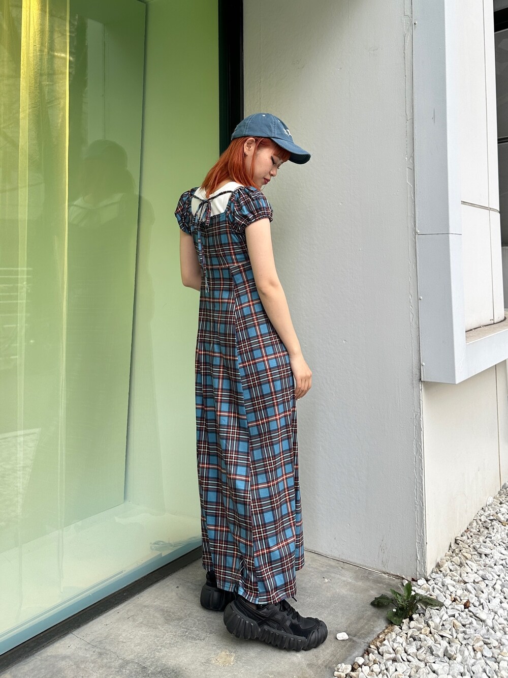 ブルー系のワンピース、ブラック系のスニーカー、ブルー系のキャップを着用したレディースの春コーディネートの2枚目の写真