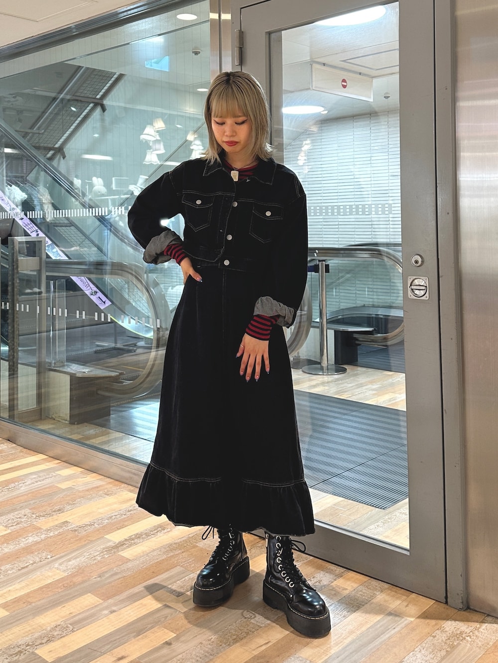 レッド系のTシャツ/カットソー、ブラック系のワンピース、ブラック系のブーツを着用したレディースの夏コーディネートの2枚目の写真