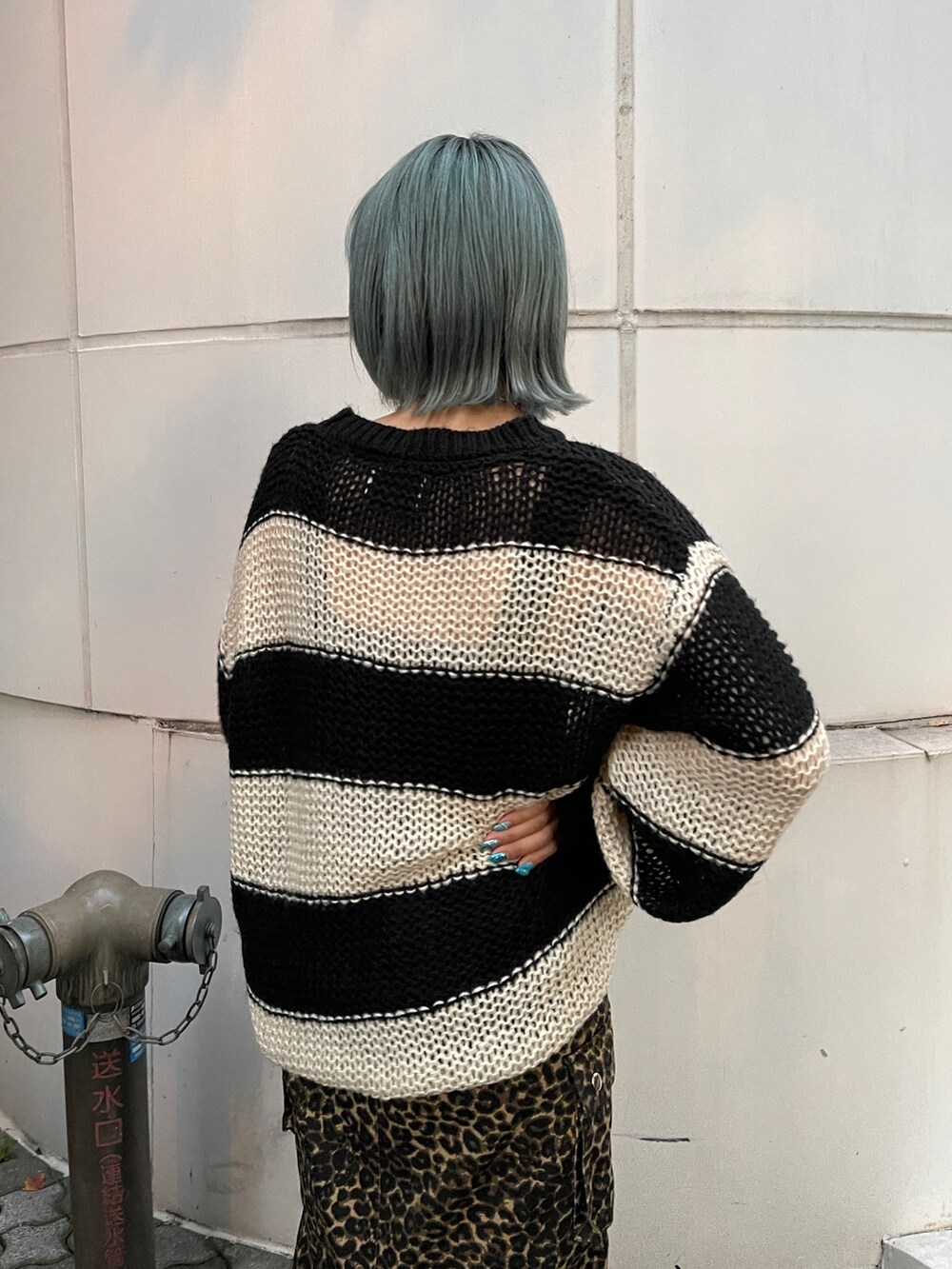 ブラウン系のスカート、ブラック系のニット/セーター、ブラック系のスニーカーを着用したレディースの秋コーディネートの5枚目の写真