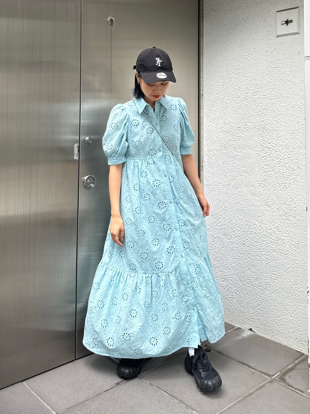 ブルー系のワンピース、ブラック系のスニーカー、ブラック系のキャップを着用したレディースの夏コーディネートの2枚目の写真