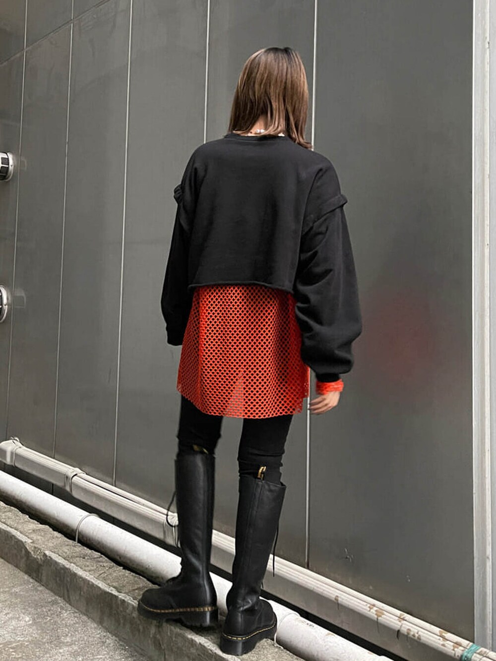 ブラック系のブーツ、ブラック系のTシャツ/カットソー、オレンジ系のTシャツ/カットソーを着用したレディースの冬コーディネートの3枚目の写真