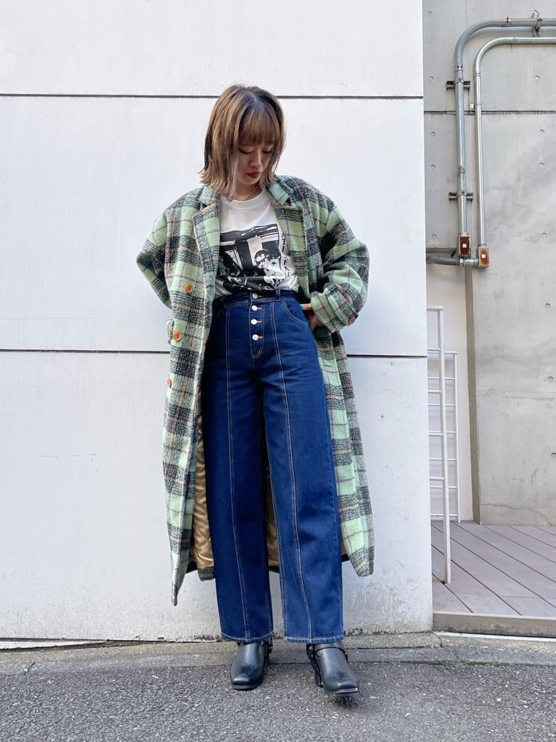 グリーン系のチェスターコート、ブラック系のブーツ、ブルー系のデニムパンツを着用したレディースの秋コーディネートの4枚目の写真
